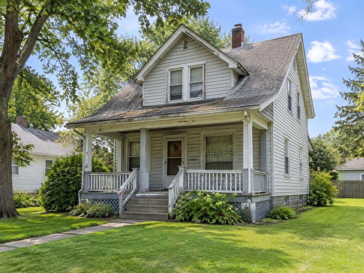 An older house with dated siding, a tired porch, and an aging roof.