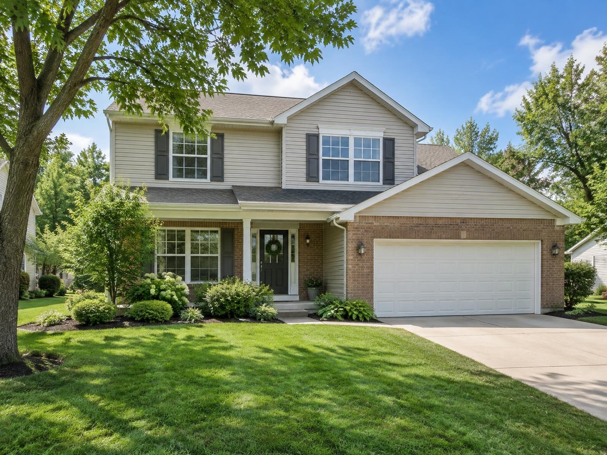 A bright two-story family house with a green lawn.