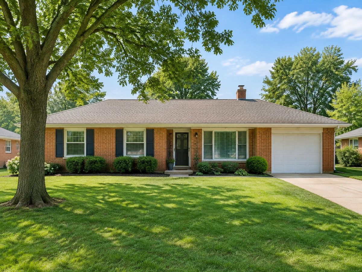 A neat brick ranch house with a trimmed front lawn.